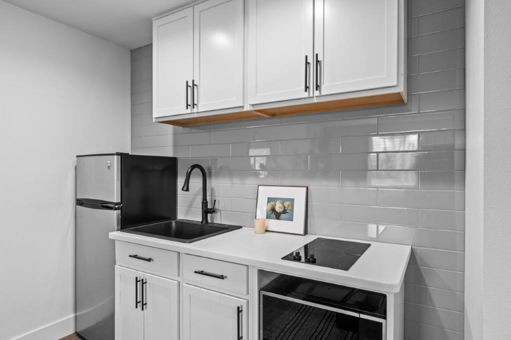 a kitchen with white cabinets and black and white tiles